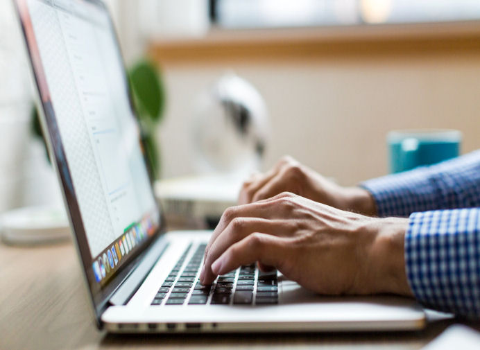 man typing on a laptop keyboard